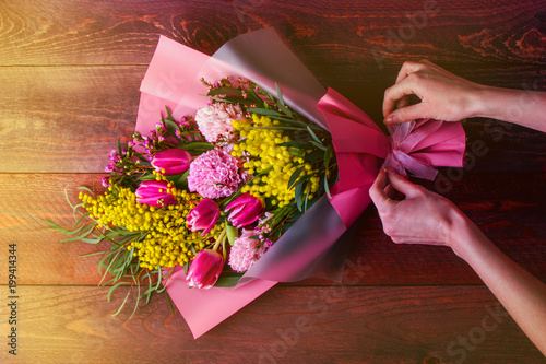 florist works packs a bouquet in Korean style with Mimosa, hyacinths and tulips