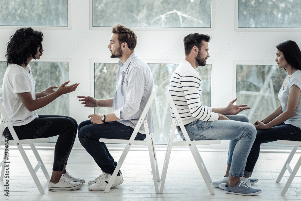 Interesting communication. Joyful positive happy couples smiling and talking while sitting opposite each other Interesting communication. Joyful positive happy couples smiling and talking while sitting opposite each other