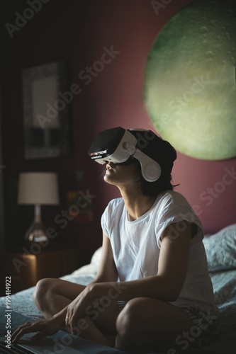 Woman using laptop with virtual reality headset in bedroomWoman photo