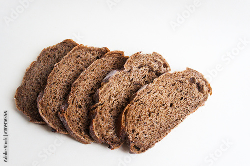 Slices of dark bread on a light paper background. Candid, copy space.