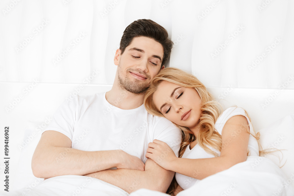 Loving couple lies in bed indoors at home. Loving couple lies in bed indoors at home.