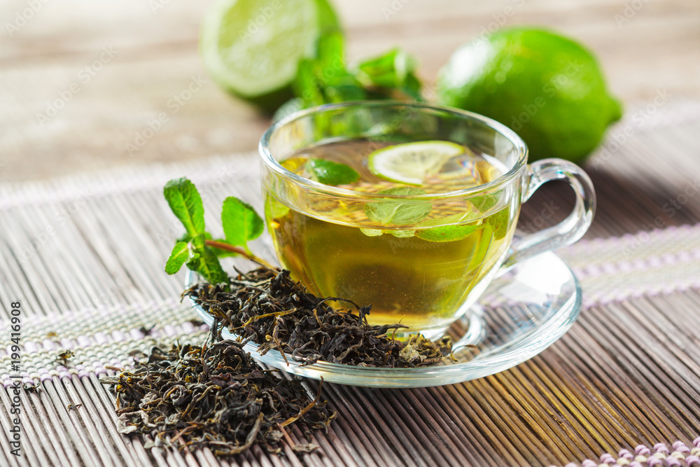 cup of black tea with mint leaves on a wooden table