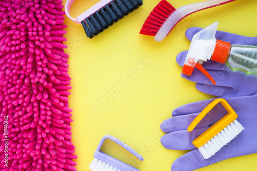 Cleaning Concept. Set of yellow  green  blue  red  white and pink cleaning tools  rags  sponges  brushes  dishwashing liquid  rubber gloves on the yellow background  top view  flat lay  close up