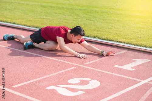 Sad young asian man runner sitting on the ground and cry after losing in competition