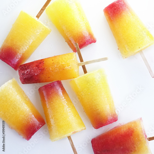 Sweet refreshing summer food concept. Ice cream fruit ice yellow orange and red colors top view on white background close up macro.