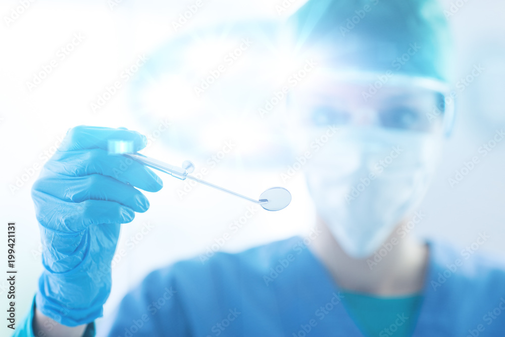 Femal dentist holding a mouth mirror Femal dentist holding a mouth mirror