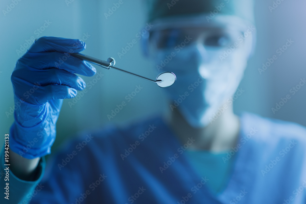 Femal dentist holding a mouth mirror Femal dentist holding a mouth mirror