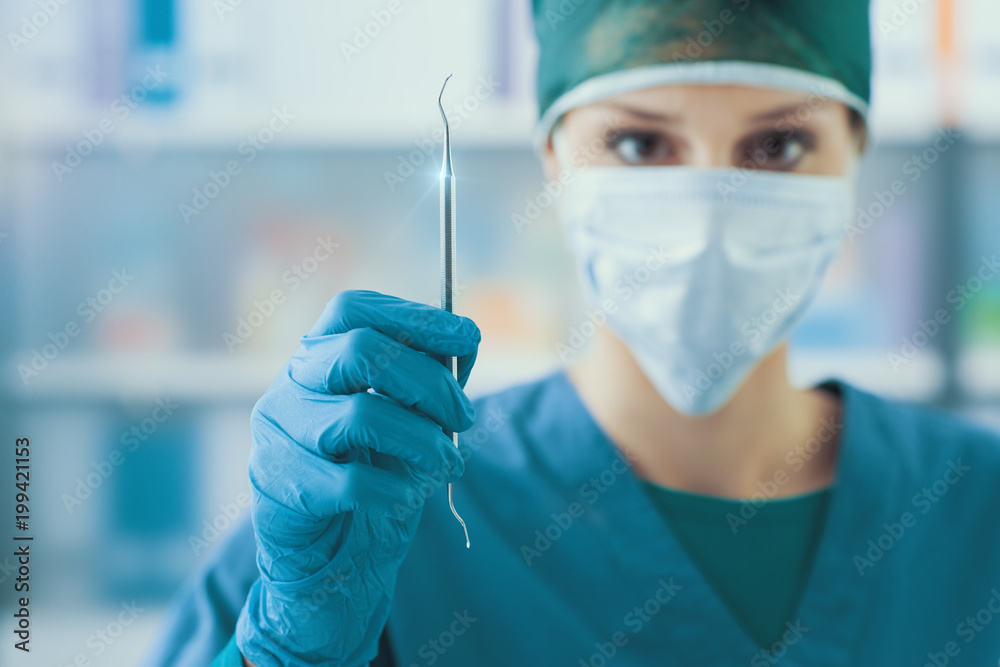 Female dentist holding a scaler Female dentist holding a scaler