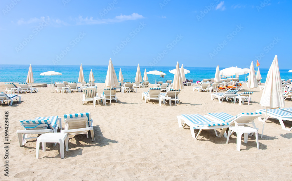 Tropical beach of Alanya. Sun beds and deckchairs on sandy sea beach on sunny, sunny day. Summer vacation concept. Tropical beach.