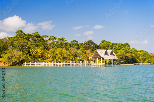 House of wood and grass on tropical beach in guatemala, santo tomas. Hut on sea shore on sunny blue sky. Summer vacation on island. Wanderlust, adventure and discovery