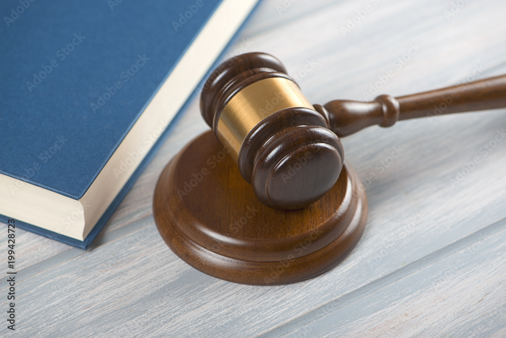 Wooden mallet used by a judge or at an auction next to a book. Concept Wooden mallet used by a judge or at an auction next to a book. Concept