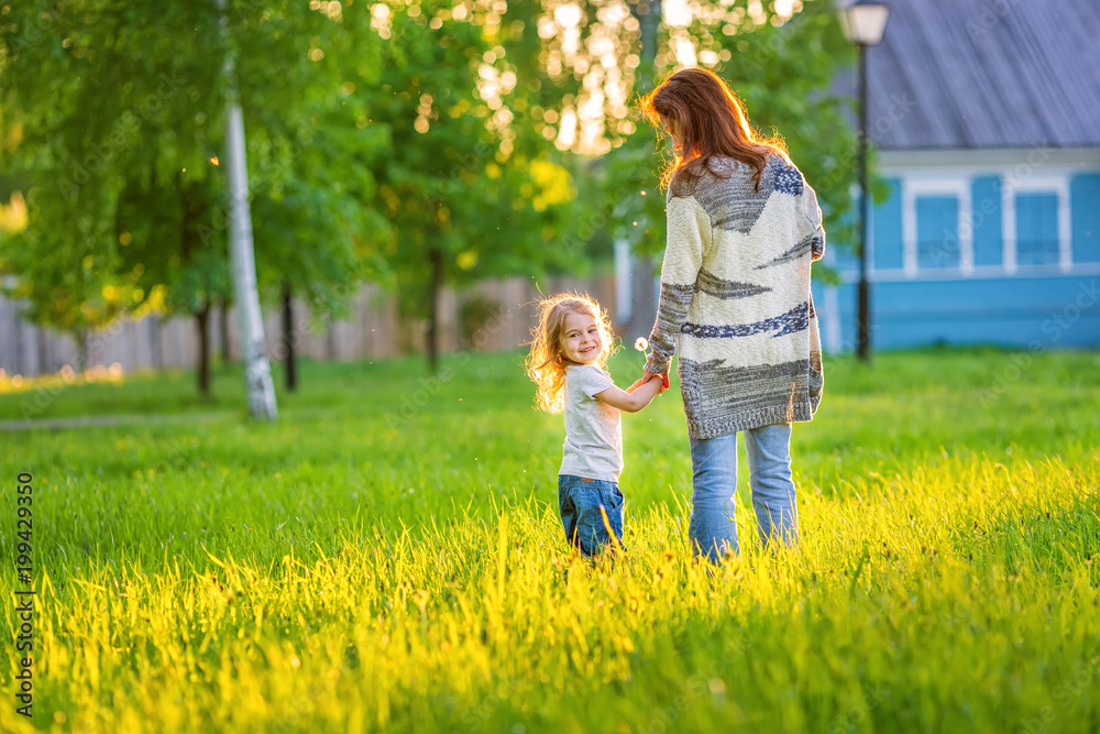 Fototapeta premium Mother and little daughter walking in spring sunny park