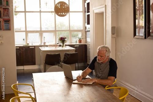 Senior man writing on a diary at home photo