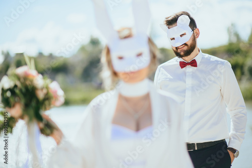 Fotografie bearded groom and beautiful bride posing in rabbit masks
