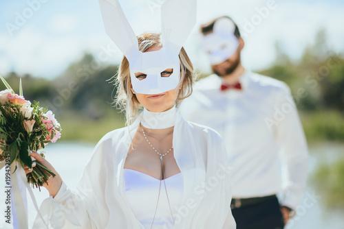 bearded groom and beautiful bride posing in rabbit masks