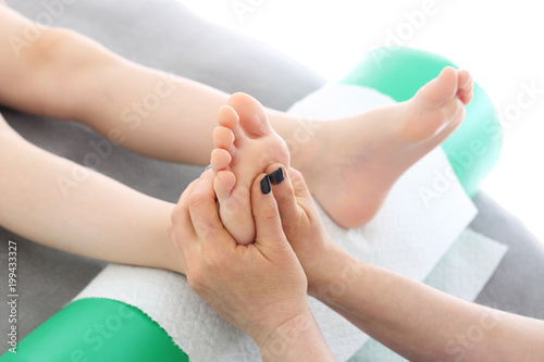 Akupresura stóp. Masażysta wykonuje punktowy masaż stopy dziecka. 