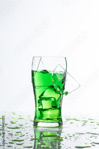 ​broken glass ice hand and green water on white background