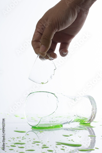 ​broken piece of glass cut hand and green water on white background