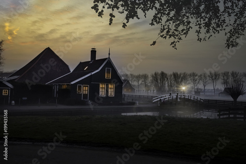Ducks flying over a beautiful typical Dutch wooden houses architecture at the sunrise moment mirrored on the calm canal of Zaanse Schans located in the North of Amsterdam, Netherlands