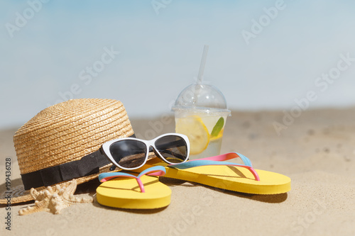 Flip flops, sunglasses and accessiores on sandy beach. holidays background. Copy space. photo