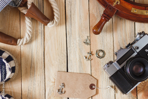 Striped slippers, camera, bag and maritime decorations on the wooden background