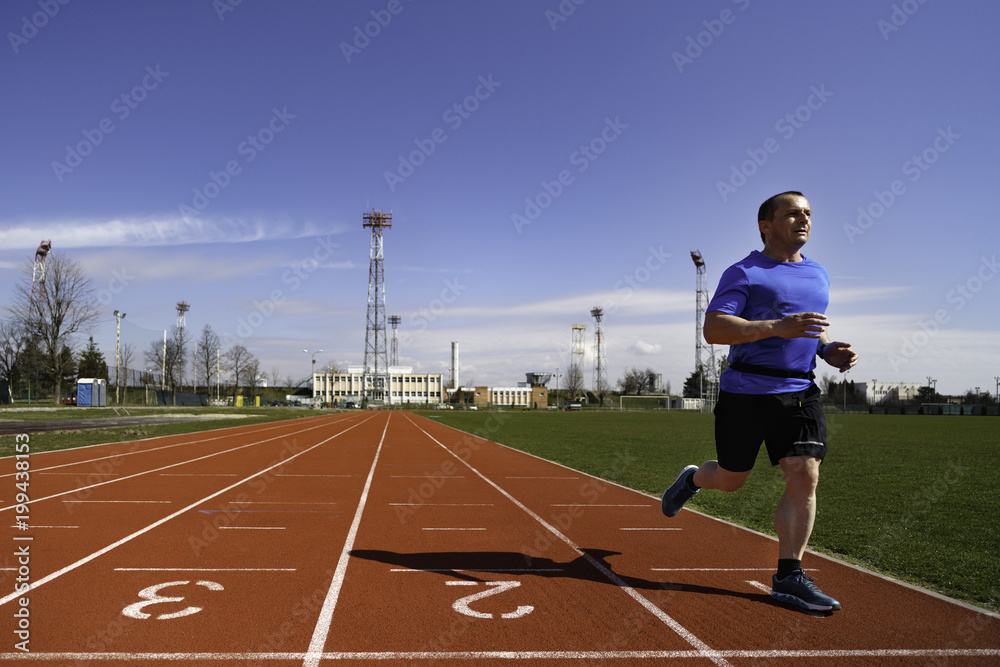 Fototapeta premium Male sprinter in middle age trains for race competition