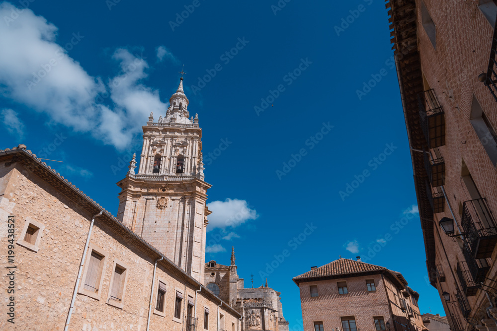 main public access to Burgo de Osma medieval town, with public street and tower of cathedral, landmark and monument from thirteenth century, in Soria, Spain, Europe