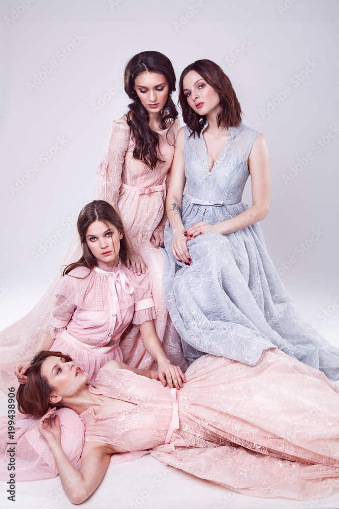 Fashion studio photo of four elgant women in pink and blue dresses