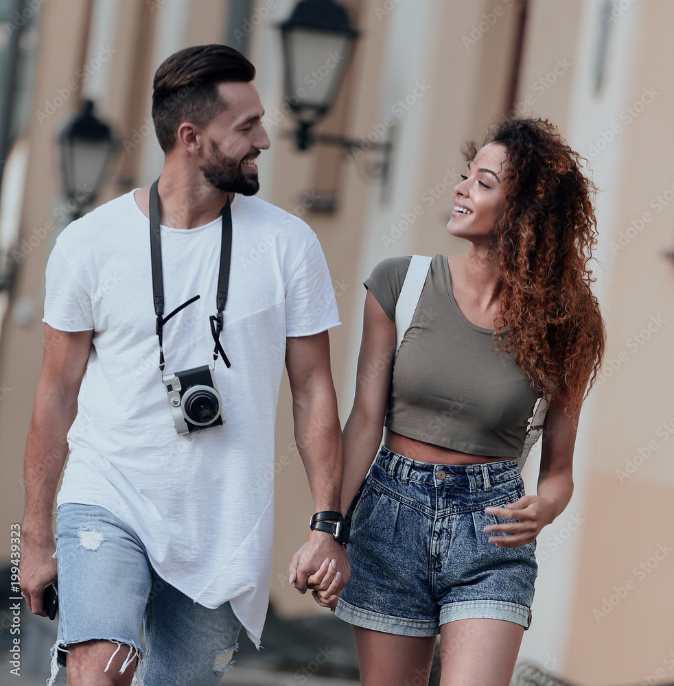 Naklejka premium A loving couple of tourists look at each other and walking