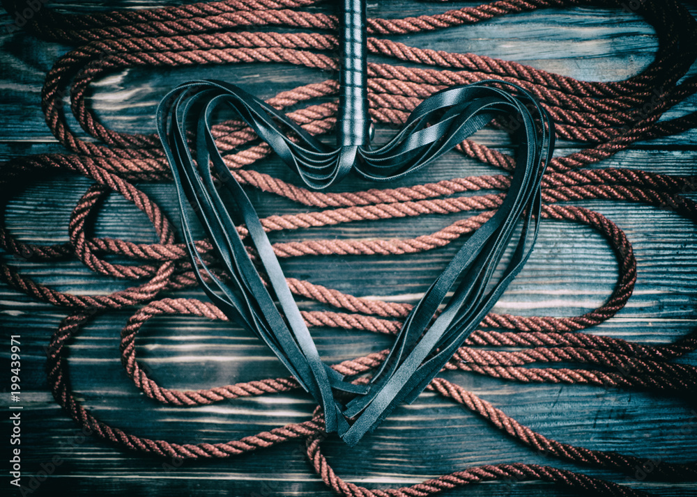 Scourge for BDSM in the form of a heart and a rope for binding on a dark  background. Accesories for sexual games. Stock-Foto | Adobe Stock