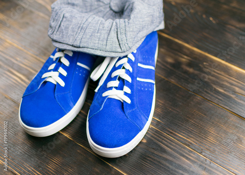 Blue leather sneakers and a cap on a wooden background.