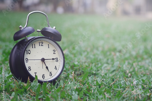 Black alarm clock on grass background