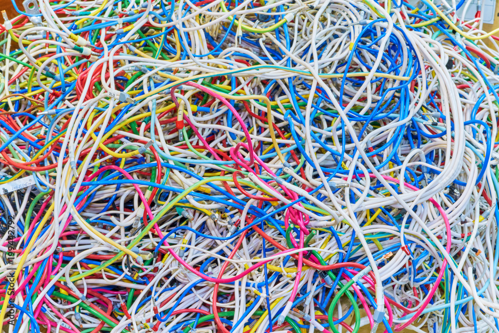 The bunch of electric wires or cables are strongly tangled together. Remnants of wires of different colors, piled in a big pile. On the wires there are compressed ferrules for connection.