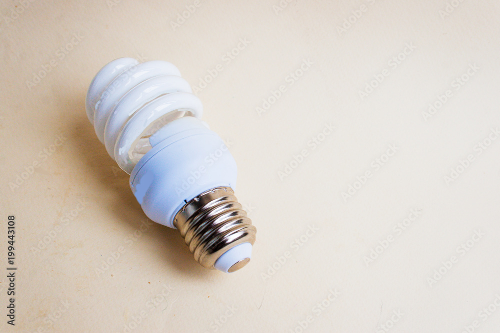 Energy-saving light bulb on a light paper background. Candid, copy space. Energy-saving light bulb on a light paper background. Candid, copy space.