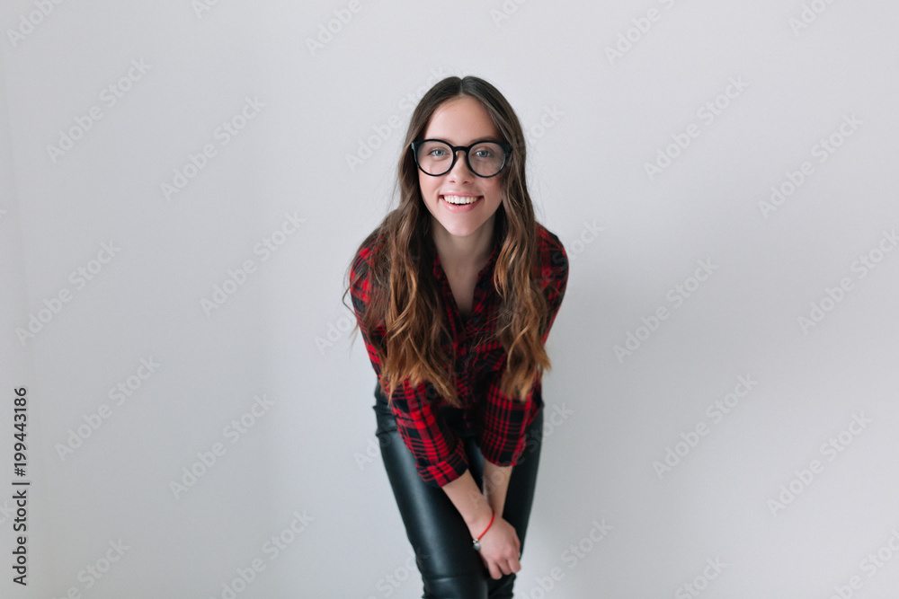 Stylish glad young woman with positive news or birthday gift, looking at camera with joyful and charming smile. Brunette student girl relaxing indoors on isolated background Stylish glad young woman with positive news or birthday gift, looking at camera with joyful and charming smile. Brunette student girl relaxing indoors on isolated background