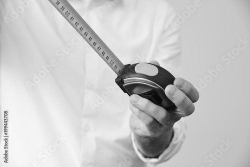 Businessman in a smart white shirt holds a measuring tape in his hand - metaphora for well planned concepts photo