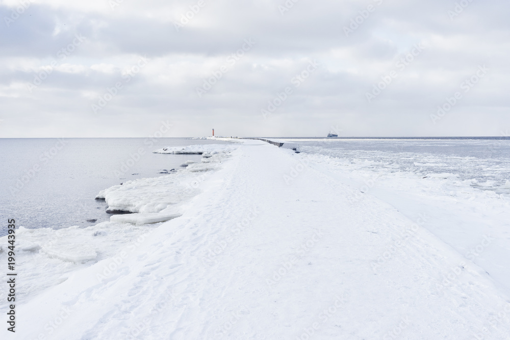 A pier to the lighthouse at the mouth in winter