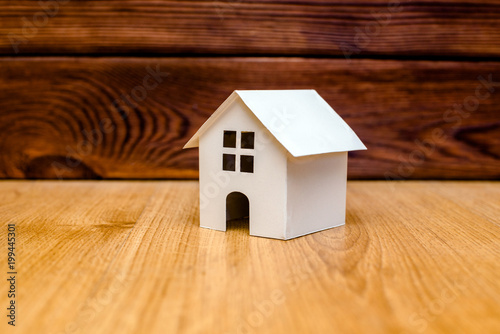 The symbol of the house stands on a brown wooden background 