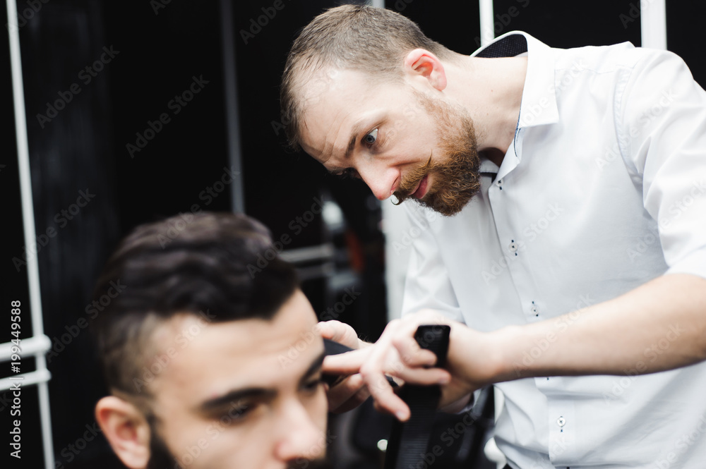 Master cuts hair and beard of men in the barbershop, hairdresser makes hairstyle for a young man Master cuts hair and beard of men in the barbershop, hairdresser makes hairstyle for a young man