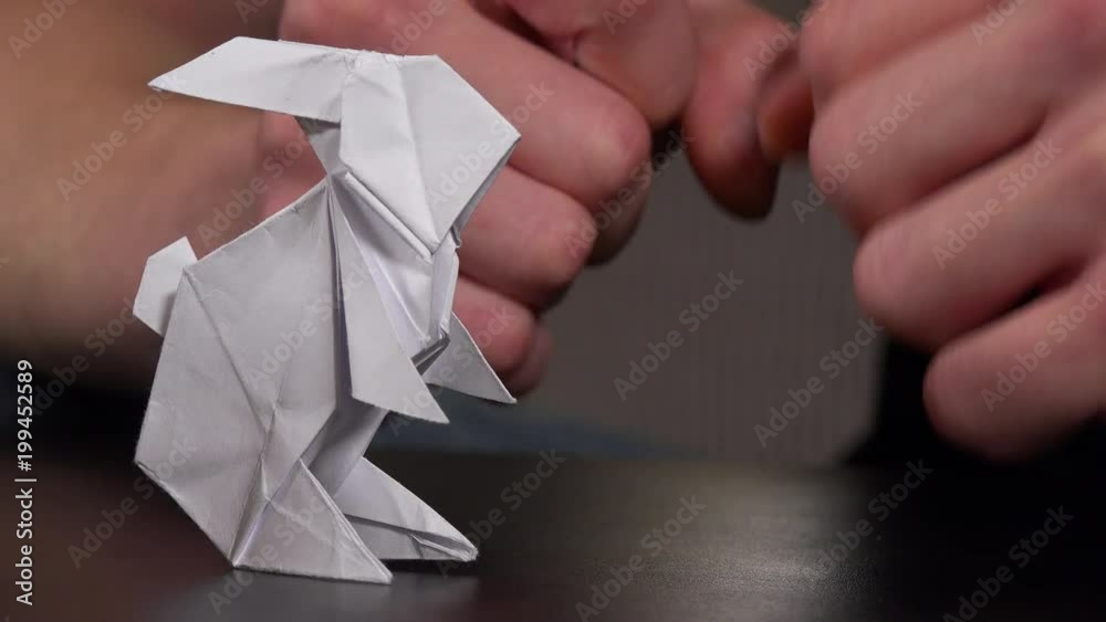 An artist makes an origami rabbit in a living room - closeup