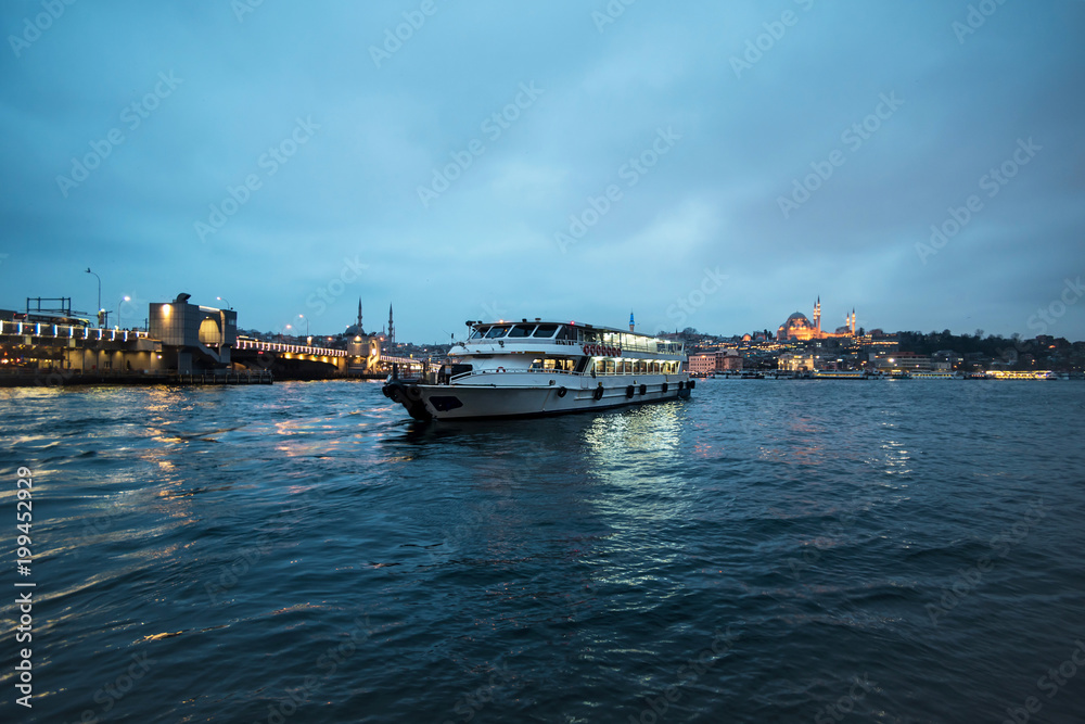 Views of Galata bridge and a ferry in Klarios river at night, Istanbul Turkey