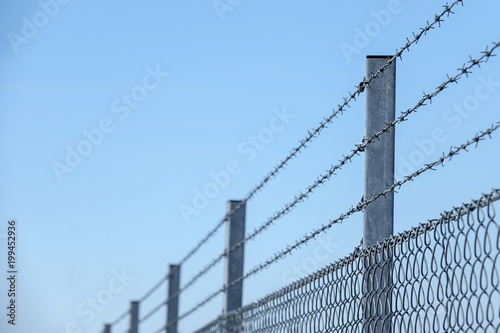 Three layers with barbed wire at the top of a fence. Copy space for text.