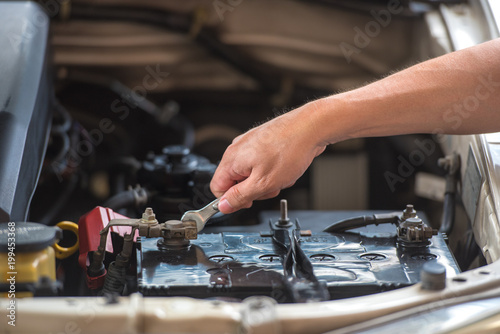 Action of man hands using spanner remove car battery terminals to change the new one, car fixing and maintenance service concept.