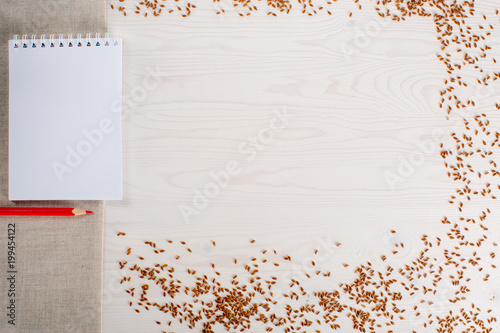 notebook with pencils for notes on white wooden table of boards with seeds
