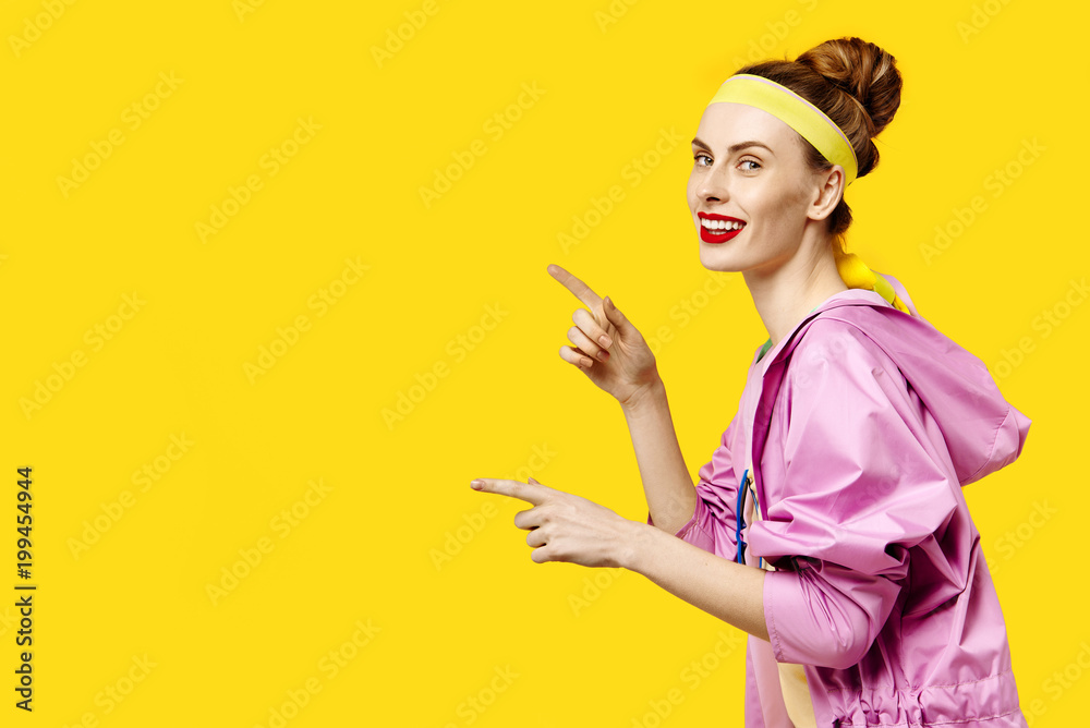 Young woman on a yellow background and pink coat. Colour obsession concept. Minimalistic style. Stylish Trendy Young woman on a yellow background and pink coat. Colour obsession concept. Minimalistic style. Stylish Trendy