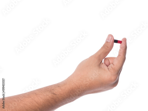 Hand holding a capsule or pill isolated on white.