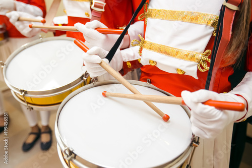 Obraz na płótnie Young girls drummers hands in red uniforms and white skirt with white gloves dru