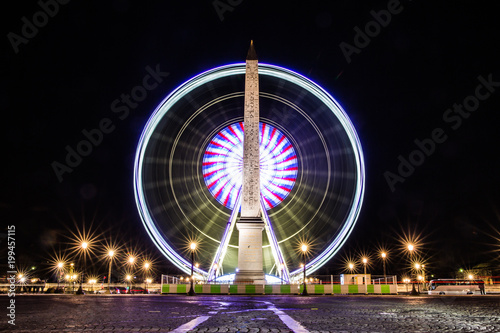 obelisk and ferris wheel at night in Paris, France