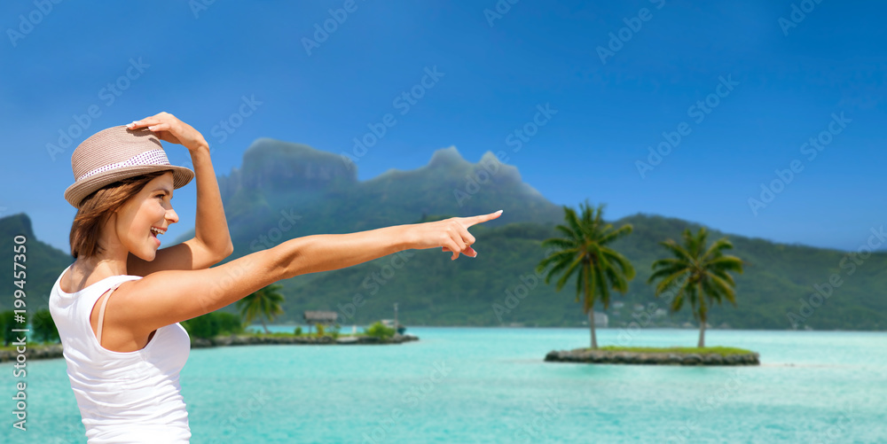 summer holidays, travel, people and vacation concept - happy young woman in hat pointing finger at touristic resort over exotic bora bora island beach background summer holidays, travel, people and vacation concept - happy young woman in hat pointing finger at touristic resort over exotic bora bora island beach background