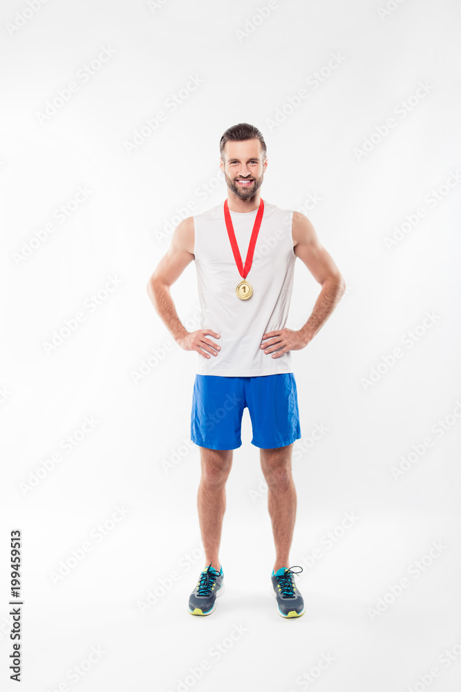 Fototapeta premium Full length, fullbody portrait of attractive, powerful, lucky, sporty, sexy, strong, athletic man having gold medal with red ribbon on his neck, hold arms on waist, isolated on white background